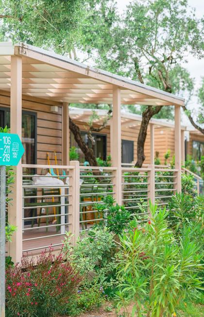 Wooden bungalows surrounded by greenery with paths and signage.