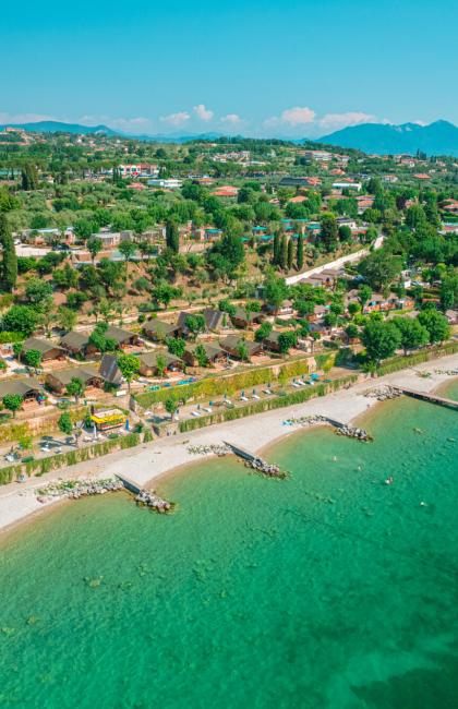 Beach with crystal-clear waters and holiday homes surrounded by greenery.