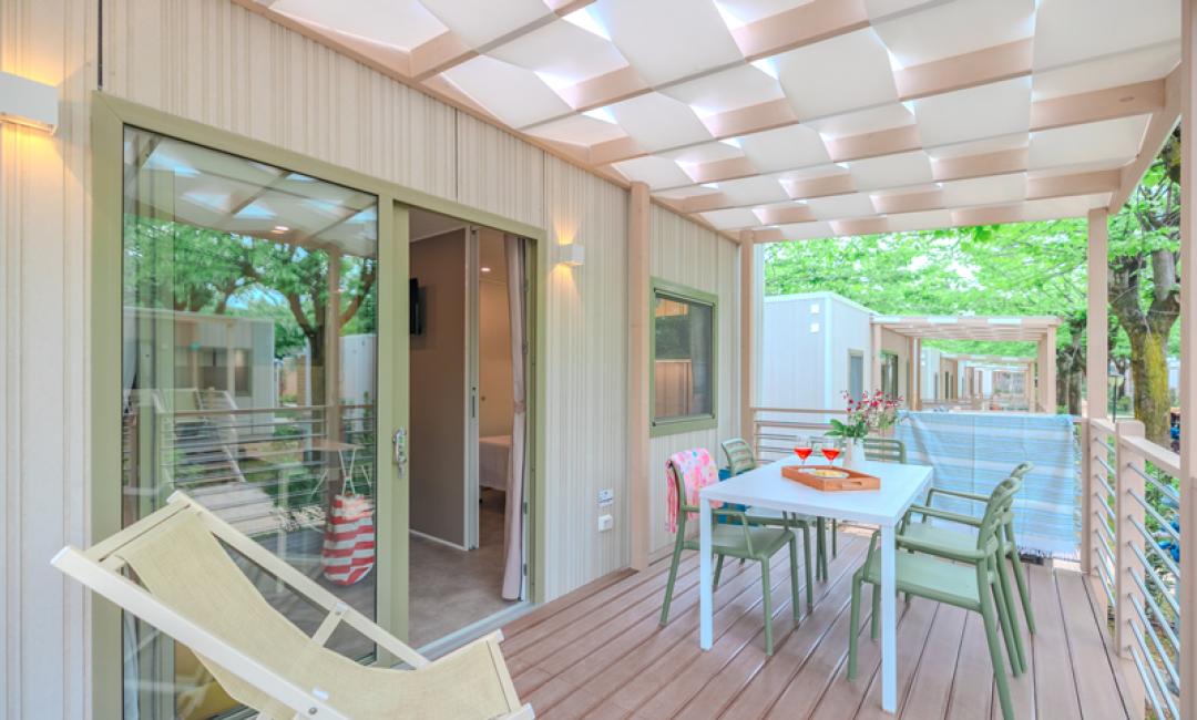 Terrazza moderna con tavolo, sedie e sdraio sotto una pergola.