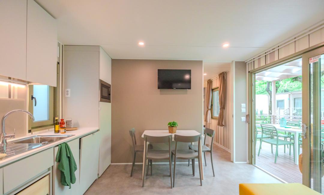 Modern kitchen-living area with table, chairs, TV, and access to the outdoor terrace.