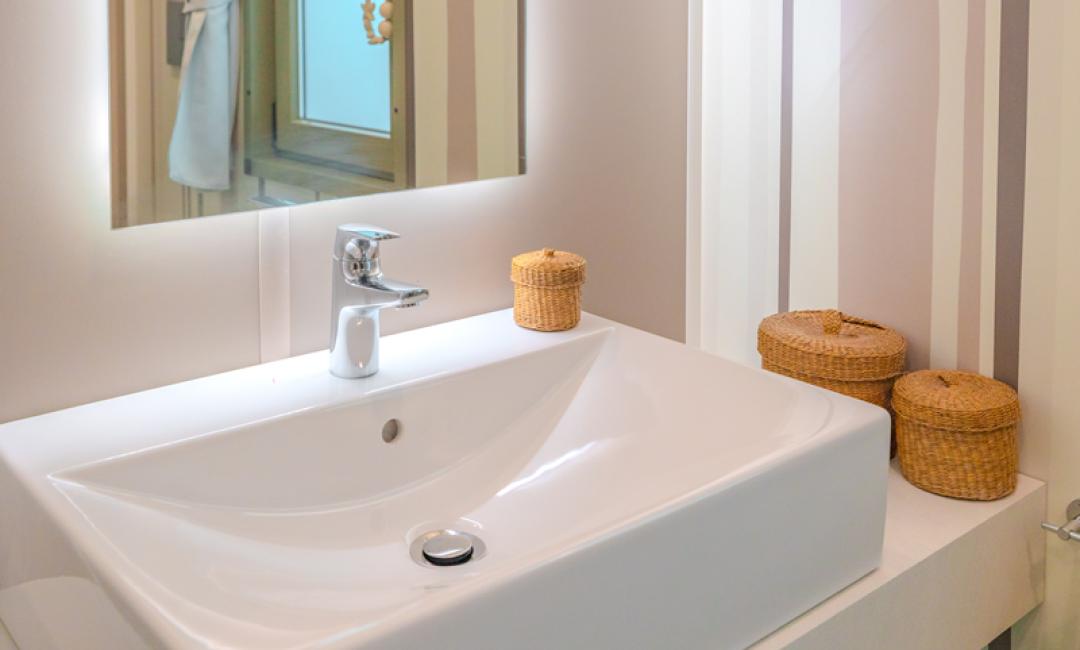 Modern sink with mirror and wicker containers.