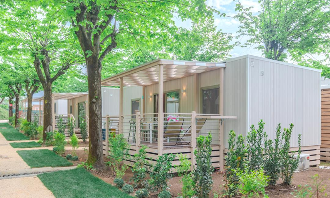 Kleine moderne Bungalows im Grünen mit Veranda und Garten.