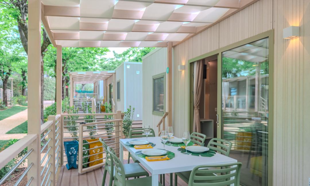 Moderne Terrasse mit gedecktem Tisch und grünen Stühlen, umgeben von Grün.