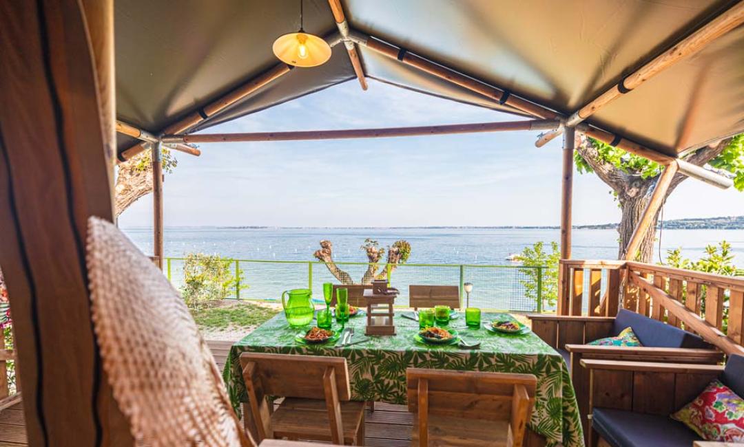 Terrazza con vista lago, tavolo apparecchiato e sedie in legno.