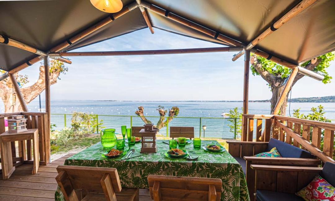 Terrazza con vista mare, tavolo apparecchiato e arredi in legno.