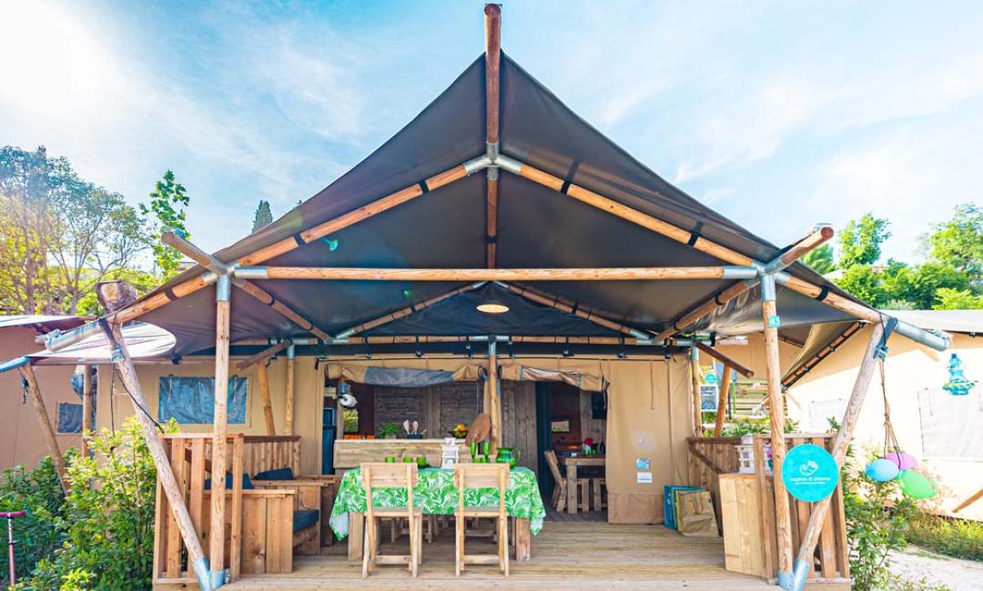 Tenda da campeggio con veranda in legno e tavolo da pranzo.