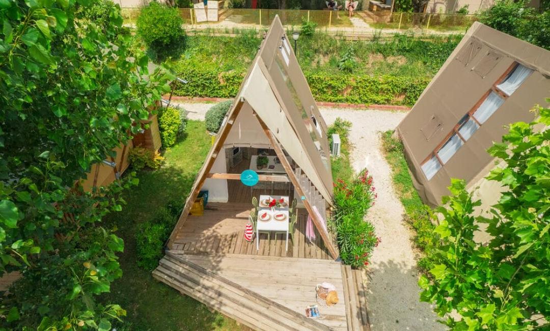 A-frame hut met terras en tuin, omgeven door natuur.