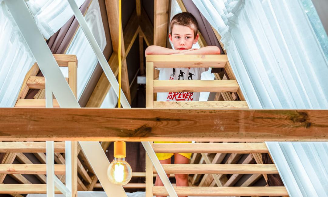 Kinderen spelen in een huis met een loft en interne trap.