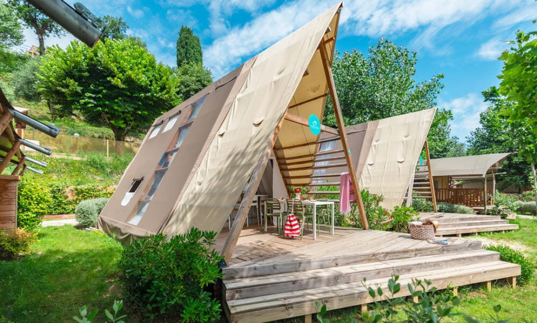 Moderne Glamping-Zelt in der Natur mit Holzterrasse.