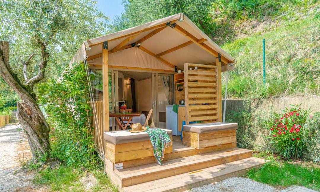 Klein houten huis met veranda omgeven door natuur.