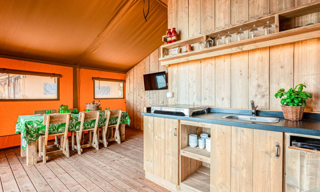 Kitchen and dining area in a glamping tent with wooden furnishings.