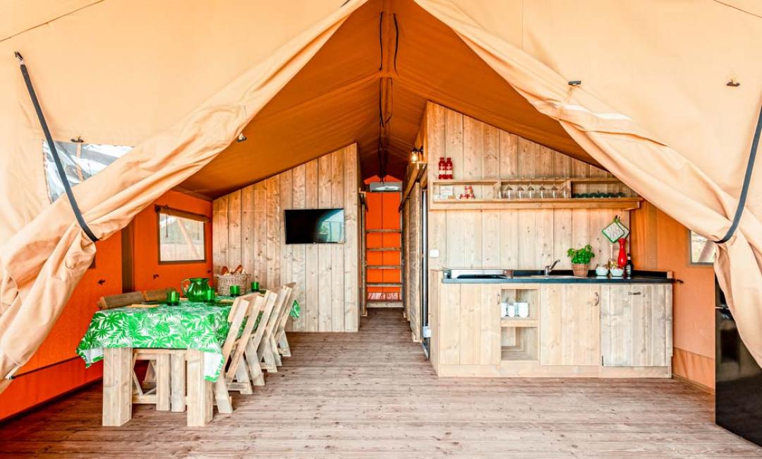 Interior of a glamping tent with a wooden kitchen and dining area.