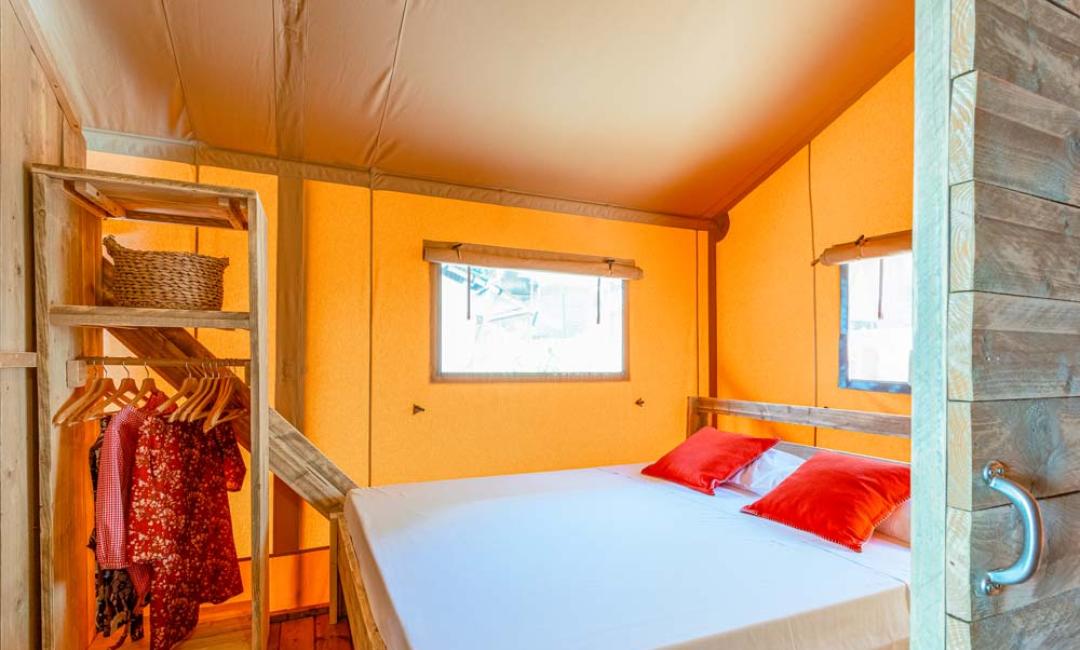 Cozy room with double bed and wooden wardrobe, decorated in warm tones.