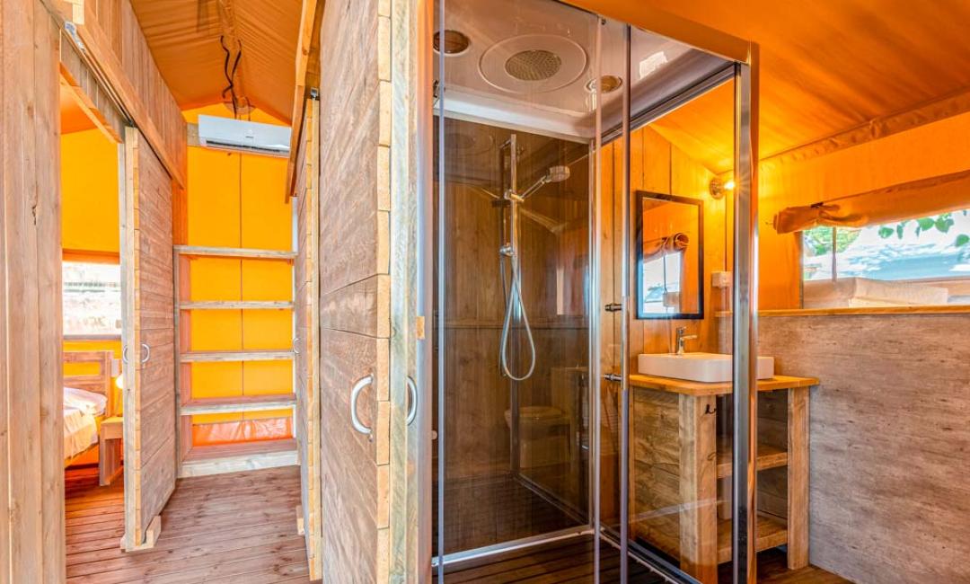 Salle de bain moderne en bois avec douche dans une tente glamping.