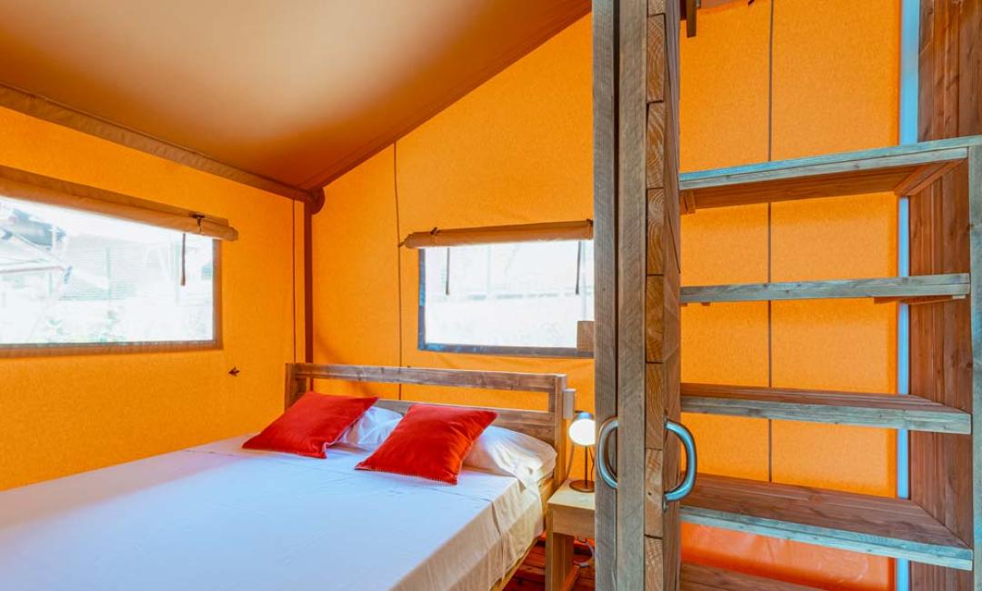 Cozy room with double bed, red pillows, and wooden stairs.