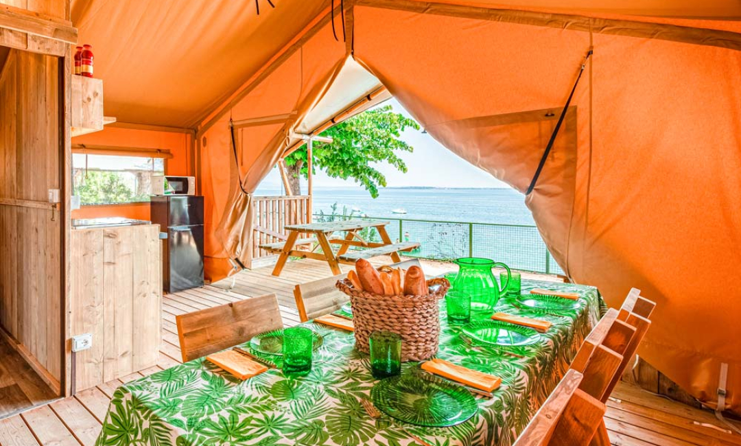 Tenda glamping con vista mare e tavolo apparecchiato.