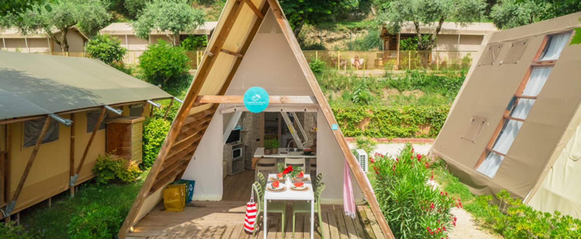 Cozy A-frame cabin surrounded by greenery, with an outdoor set dining table.
