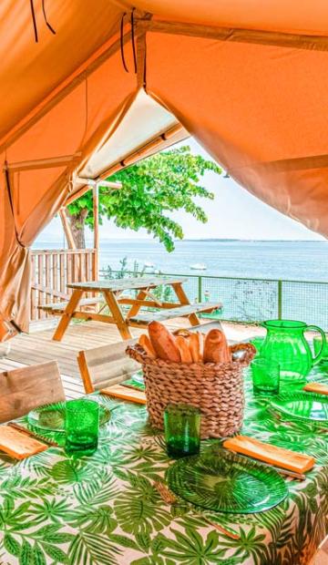 Tenda glamping con vista mare e tavolo apparecchiato.