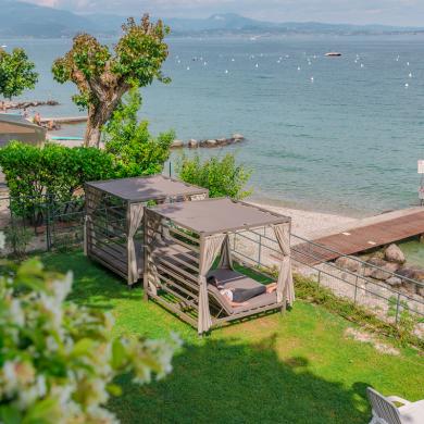 Ruhiger Strand mit Liegen unter Pavillons, See- und Bergblick.