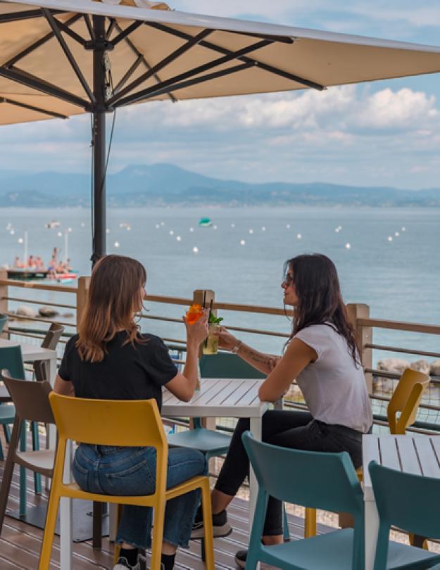 Zwei Frauen stoßen in einer Bar am Meer an.