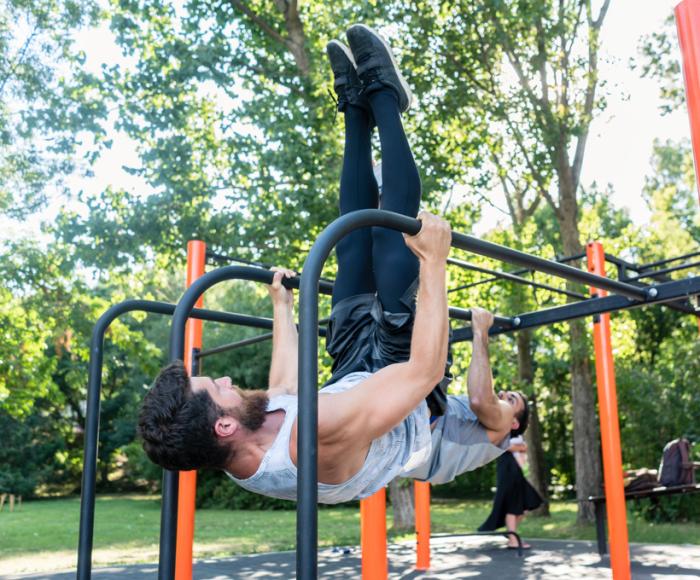 Mann trainiert an Stangen im Freien in einem Park.