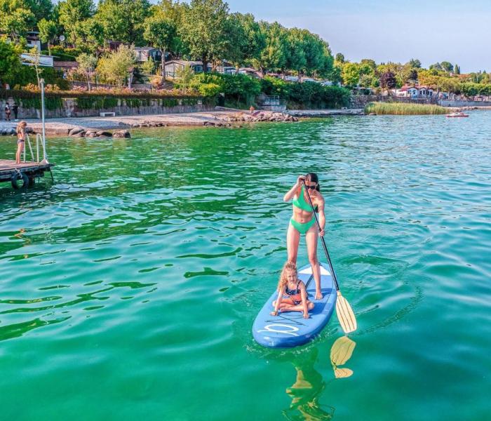 Kvinde og barn på et paddleboard i en grøn sø.